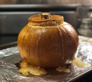 Beautifully cooked Swiss pumpkin with top of pumpkin pushing out and cheese melting over sides.
